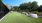 a grassy area with a fence and trees in the background